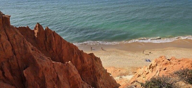 Rødlige klipper og turkist hav ved Praia da Falésia i Algarve
