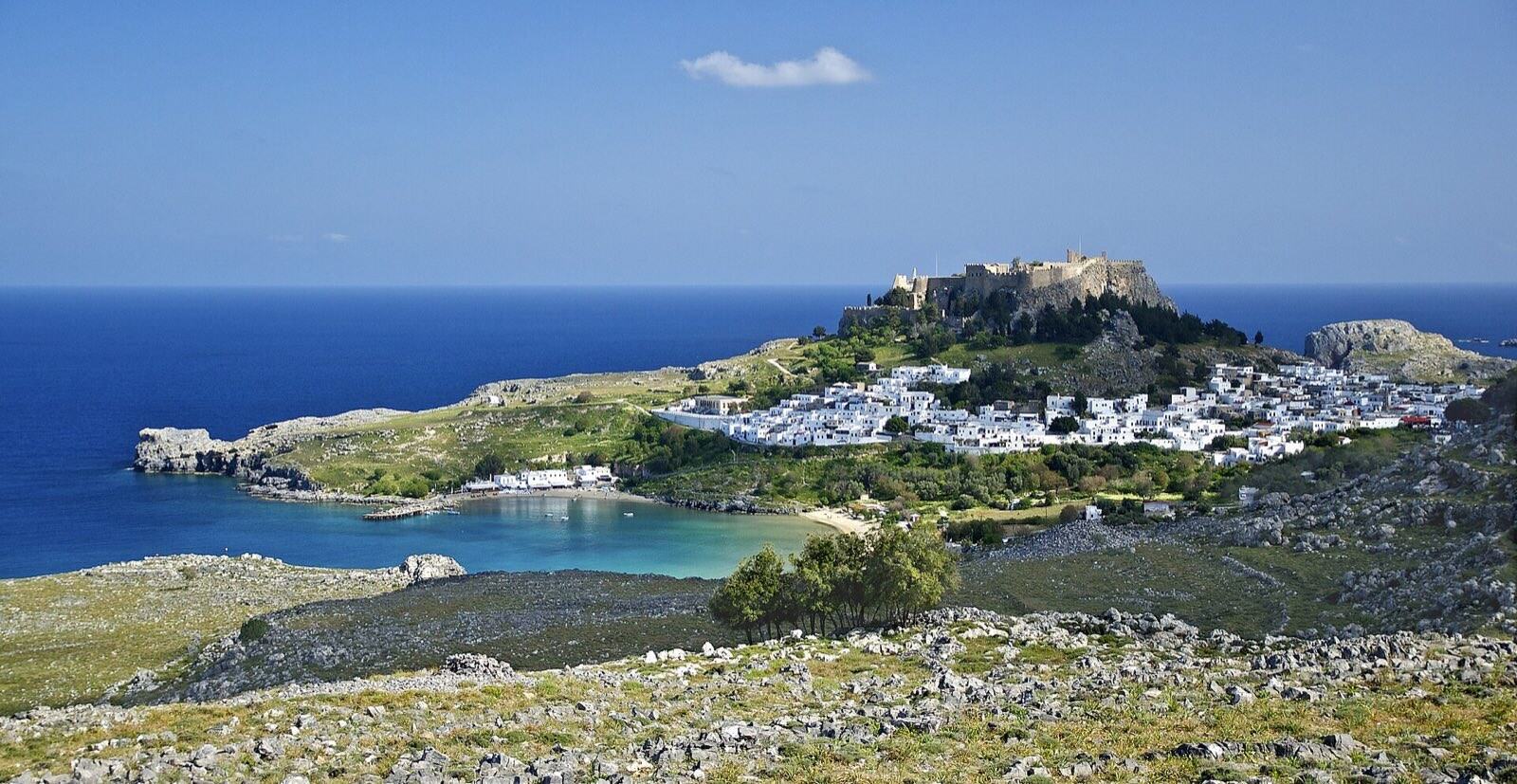 Akropolis og hvitkalkede hus i Lindos på Rhodos med bukten under