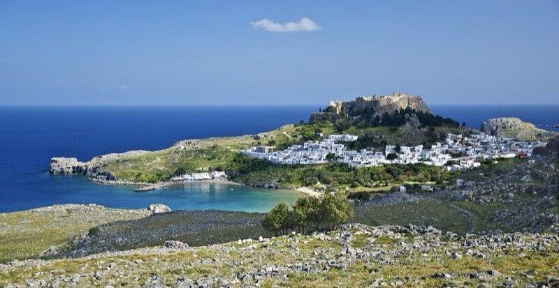 Akropolis og hvitkalkede hus i Lindos på Rhodos med bukten under