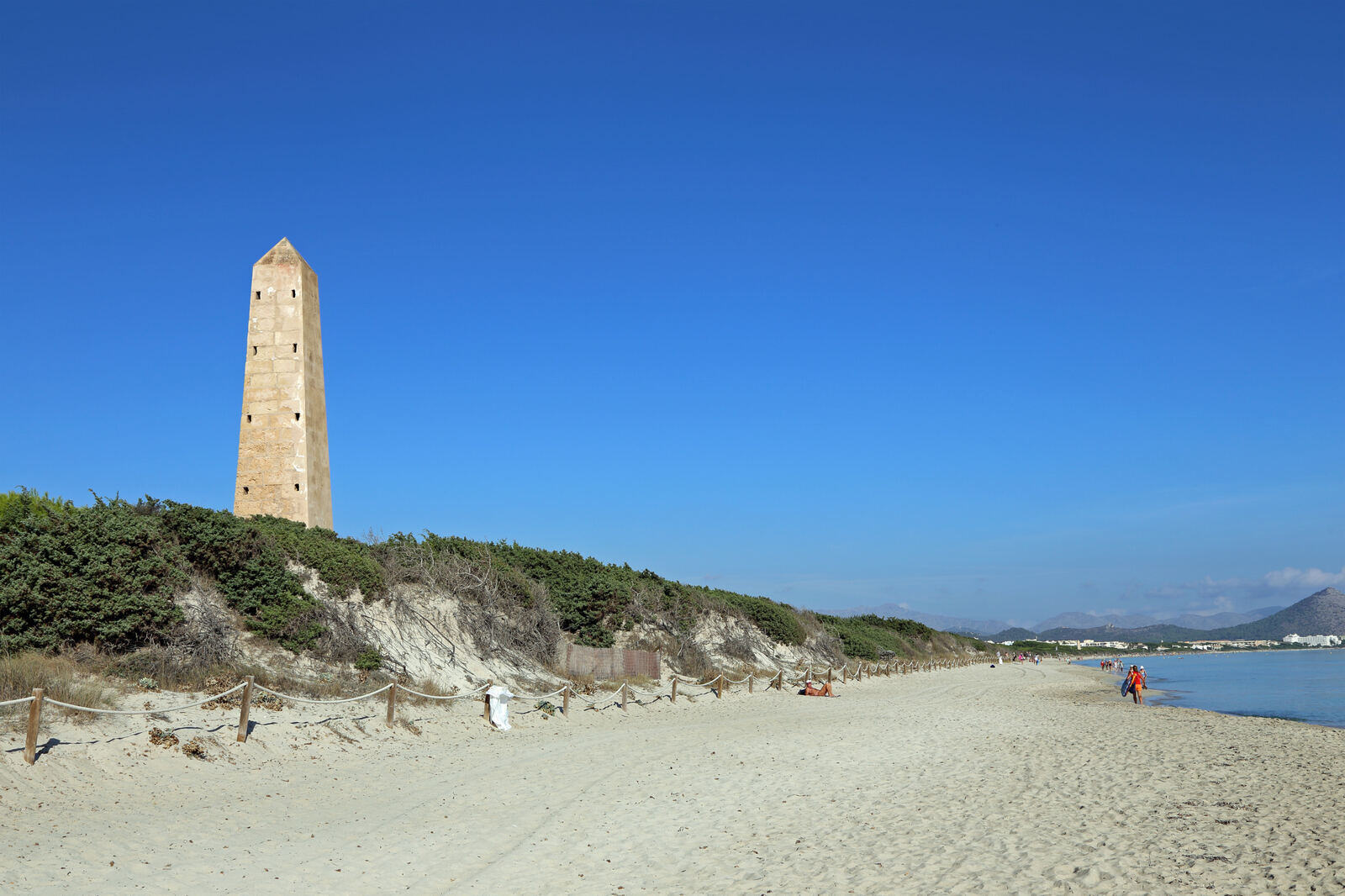 Rolig, nesten folketom strand ved Platja de Muro på Mallorca med vakttårn i dynene
