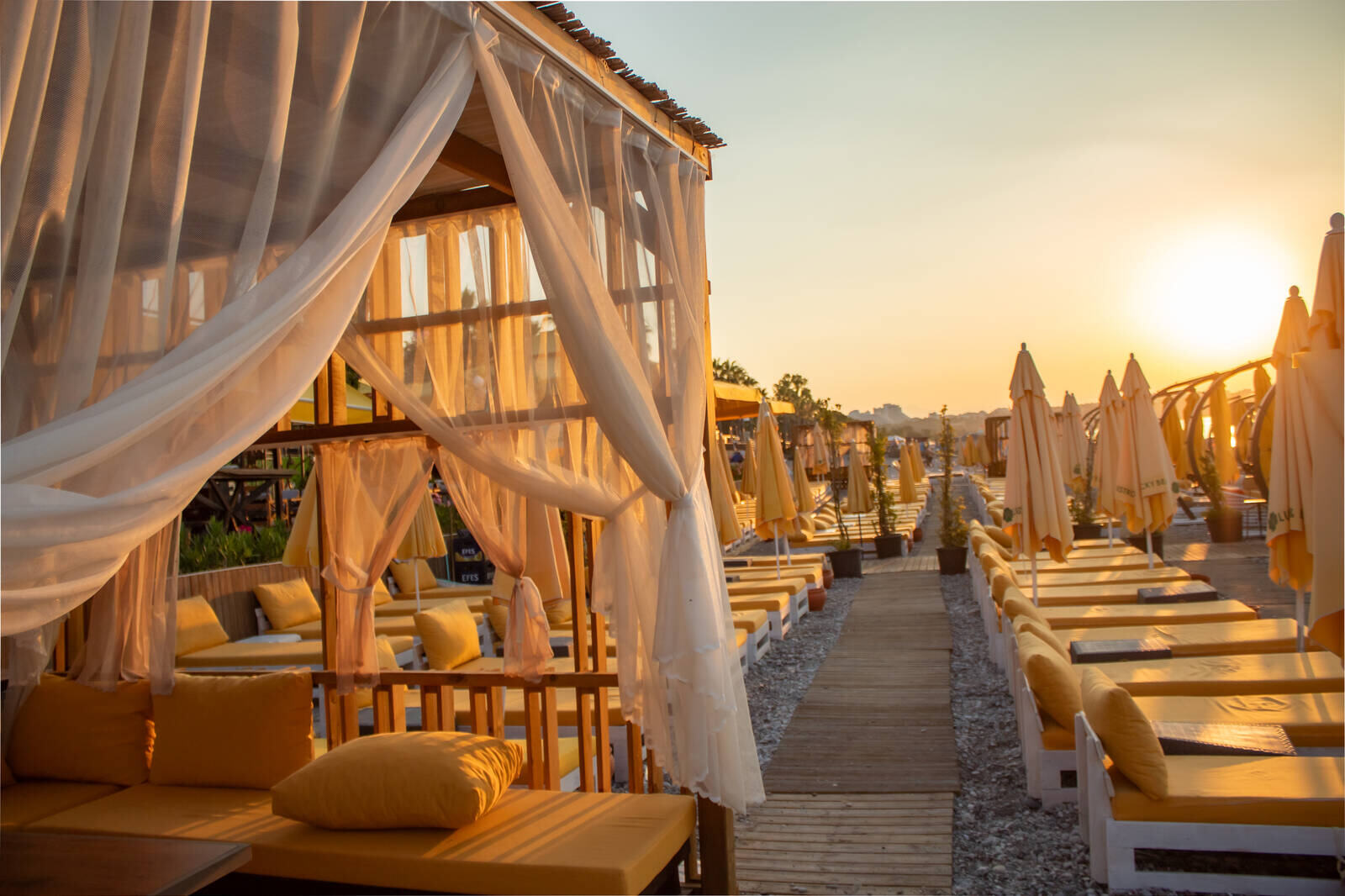 Tomme solsenger og loungemøbler ved en strandklubb i Antalya i varmt morgenlys
